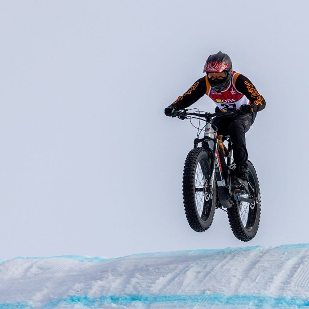 A racer catching air off a jump in the Shifty Drift downhill winter fat bike race in Anchorage, Alaska