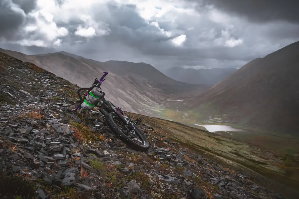 Mountain Bike leaning on a ridge with panoramic view of an Alaskan valley.